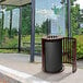 A black Ex-Cell Kaiser Streetscape coffee gloss outdoor trash can on a sidewalk.