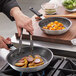 A person cooking food in a Choice aluminum non-stick frying pan.