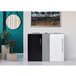 A black and white rectangular paper trash can with a green plant inside.