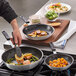 A person cooking food in a Choice aluminum frying pan.