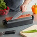 A person using a Mercer Culinary knife to cut strawberries and parsley on a cutting board.