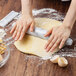 A person rolling out marbled dough on a table with a Fox Run white marble tapered French rolling pin.