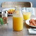 An American Metalcraft glass bottle of orange juice on a table with breakfast.