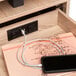 A black Safco daisy chain power module charging a phone and notebook.