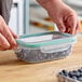 A hand holding a clear rectangular OXO plastic container with blueberries in it.
