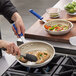 A person cooking brussels sprouts in a Vollrath Wear-Ever blue aluminum non-stick frying pan.