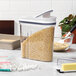 A rectangular OXO food storage container with a white lid filled with rice on a kitchen counter.