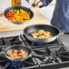 A person cooking food in a Vollrath Wear-Ever fry pan.