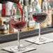 An Arcoroc Romeo wine glass filled with red wine on a table.