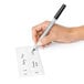 A hand holding a pen writing on an OXO Good Grips POP Removable label