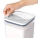 A hand using an OXO Good Grips POP removable label on a container of flour.