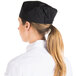 A woman wearing a black Chef Revival baker's skull cap with a black mesh top.