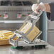 A person using a Garde cheese slicer to cut cheese.