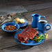 A table with a Campfire ocean blue stoneware plate of food and a blue mug of coffee.