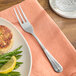 A Vollrath Queen Anne dinner fork on a plate with fish, asparagus, and a lemon wedge.