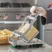 A person using a Garde cheese slicer to cut cheese.
