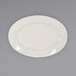 An International Tableware Roma ivory stoneware platter with a wide rim on a gray surface.
