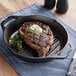 A Lodge cast iron grill pan with a steak cooking in it.