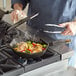 A man using a FINEX cast iron skillet to cook food on a stove.