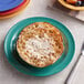 A yellow Elite Global Solutions round melamine plate with food, a knife, and a fork.