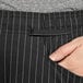 A close-up of a person's hand in a Uncommon Chef pinstripe chef pants pocket.