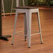 A Lancaster Table & Seating nickel gray backless counter height stool with a walnut wood seat.