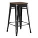 A Lancaster Table & Seating black metal backless counter height stool with a walnut wood seat.