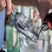 A person using a Vollrath aluminum ice scoop to add ice to a glass.