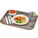 A Cambro dark oak fiberglass tray with food, a bowl of strawberries, and a fork.