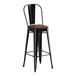 A Lancaster Table & Seating black metal barstool with a walnut wood seat.