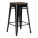 A Lancaster Table & Seating black metal backless counter height stool with a walnut wood seat.