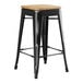 A Lancaster Table & Seating black metal backless counter height stool with a natural wood seat.