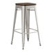 A Lancaster Table & Seating silver metal backless barstool with a walnut wood seat.