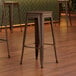 Three Lancaster Table & Seating copper backless bar stools with walnut seats at a table in a coffee shop.