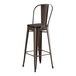 A brown metal Lancaster Table & Seating barstool with a black seat.
