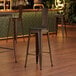 A Lancaster Table & Seating copper barstool with a black wood seat.