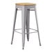 A Lancaster Table & Seating gray metal barstool with a natural wood seat.