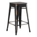 A black Lancaster Table & Seating backless counter height stool with a brown wood seat.