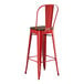 A red metal Lancaster Table & Seating barstool with a brown seat.