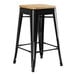 A Lancaster Table & Seating black metal backless counter height stool with a natural wood seat.