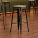 Three Lancaster Table & Seating distressed copper barstools with natural wood seats at a table in a coffee shop.