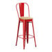 A red metal Lancaster Table & Seating barstool with a wooden seat.