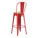 A Lancaster Table & Seating red metal barstool with a natural wood seat.