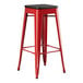 A Lancaster Table & Seating red metal barstool with a black seat.