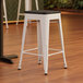 A Lancaster Table & Seating white stool with a black seat.