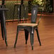 A Lancaster Table & Seating black metal cafe chair with a natural wood seat.