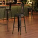 A Lancaster Table & Seating black metal barstool with a black wood seat.