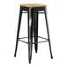 A Lancaster Table & Seating black metal barstool with natural wood seat.
