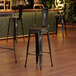 A Lancaster Table & Seating black barstool with a walnut wood seat.