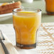 A Carlisle Louis smoke plastic tumbler filled with orange juice on a table.
